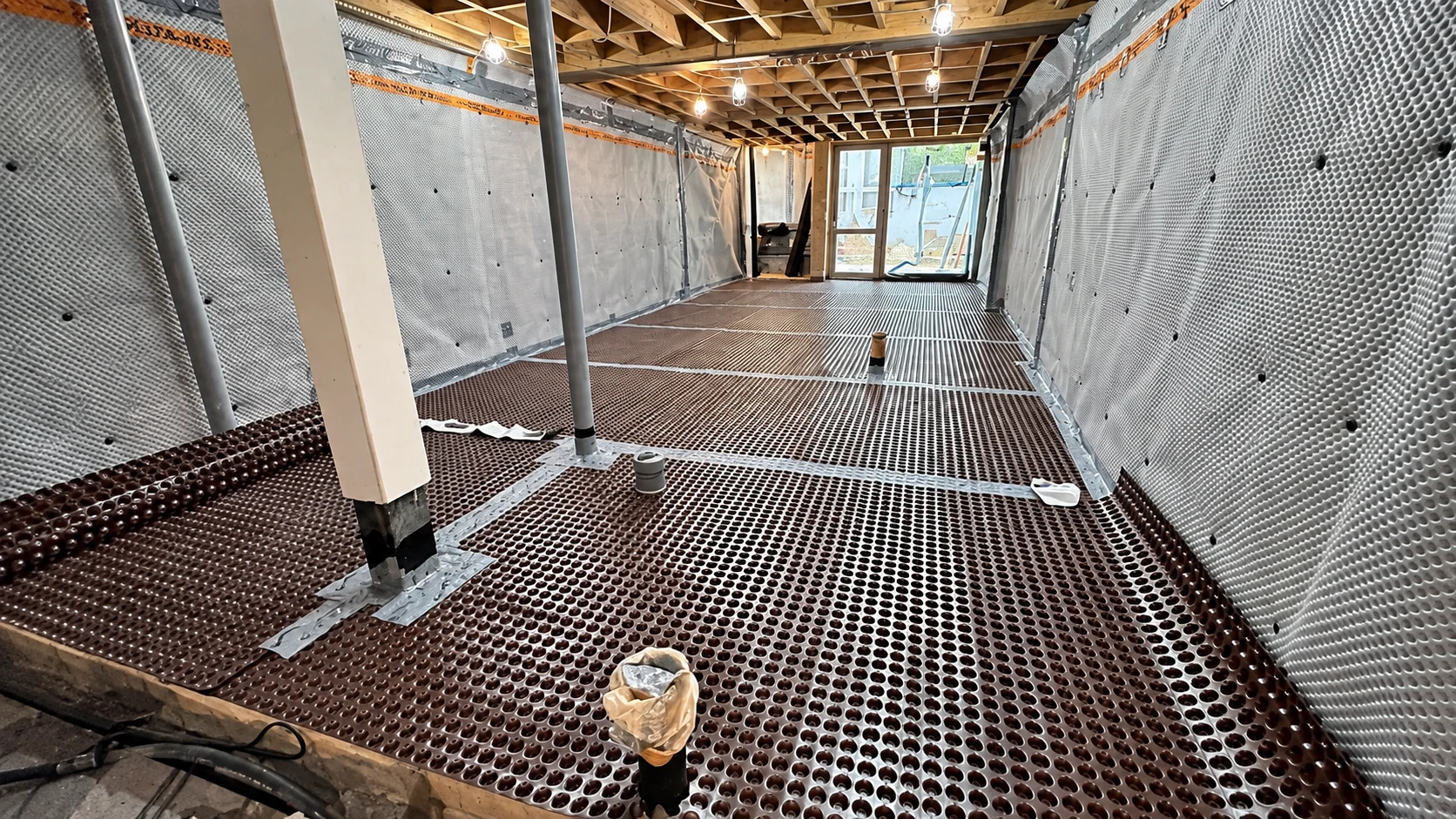 Delta Type C cavity-drain waterproofing system installed across a basement floor and walls by LNK